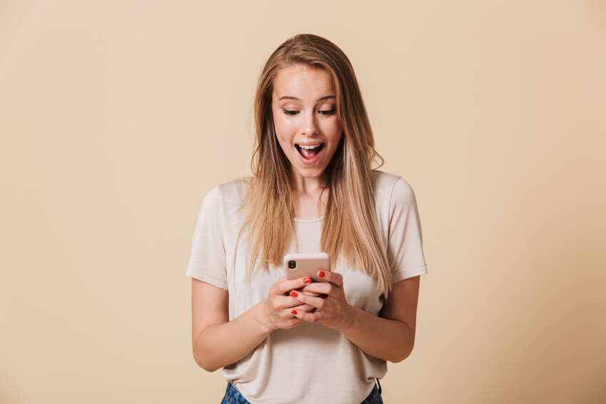 Eine glückliche Frau, die in einer Dating-App auf ihrem Handy schreibt