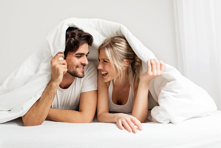 Christliches Paar lächelt unter dem Bettlaken