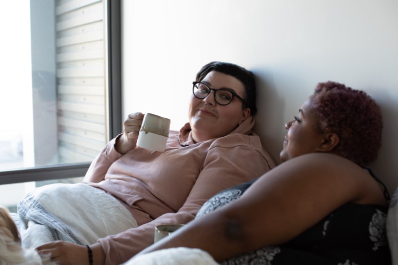 Lesbisches Paar im Bett mit einer Tasse Kaffee