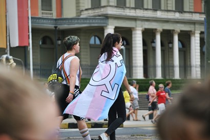 zwei Personen mit einer Transgender-Flagge bei einer Pride-Parade