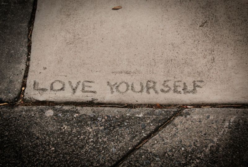 Liebe dich selbst auf einem Bürgersteig geschrieben