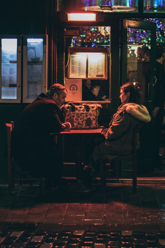 ein Mann und eine Frau sitzen vor einem Restaurant und führen ein ernstes Gespräch